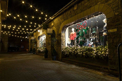 Ashtrees Way, Carnforth showing Kitty Brown Boutique with Christmas decorations and festoon lights across the pedestrianised street