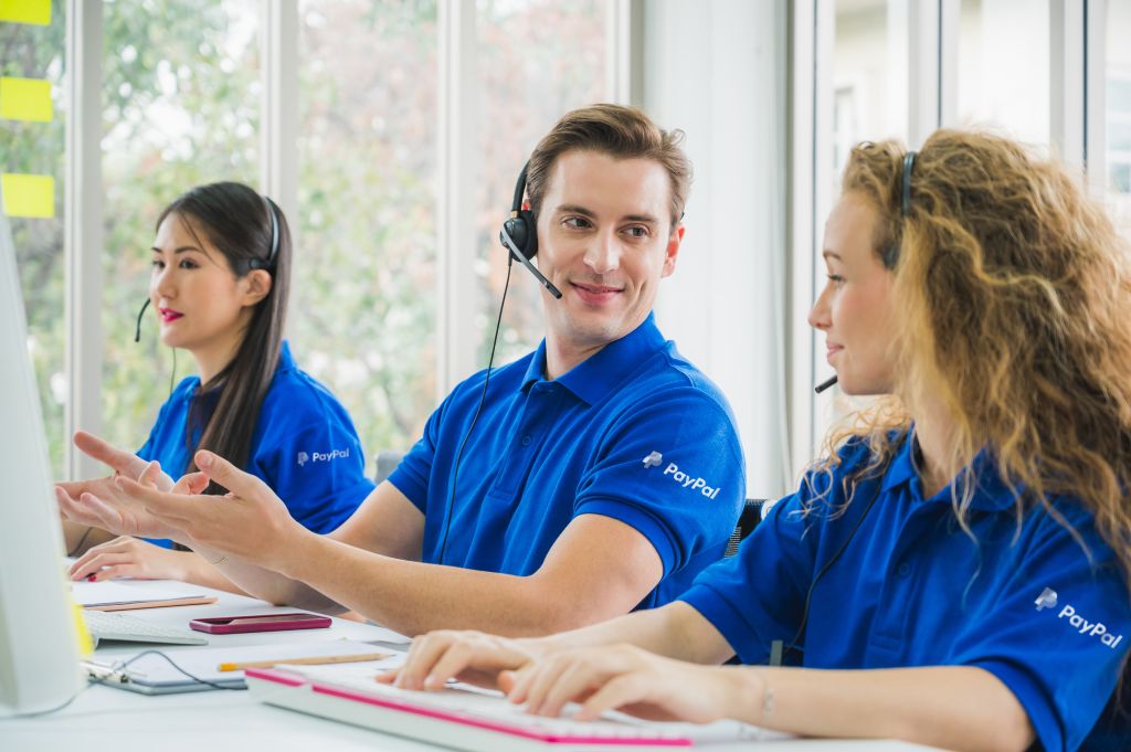 Customer support operators in blue uniforms work at office call center.