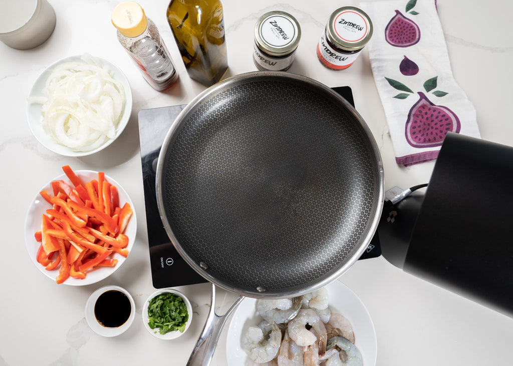 ingredients used to create Zindrew's Shrimp Stir-fry on a counter top with a pan to cook it in in the middle