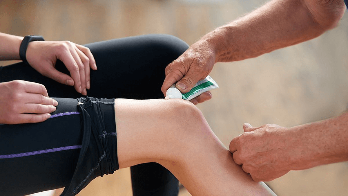 older person applying topical to a younger persona's knee