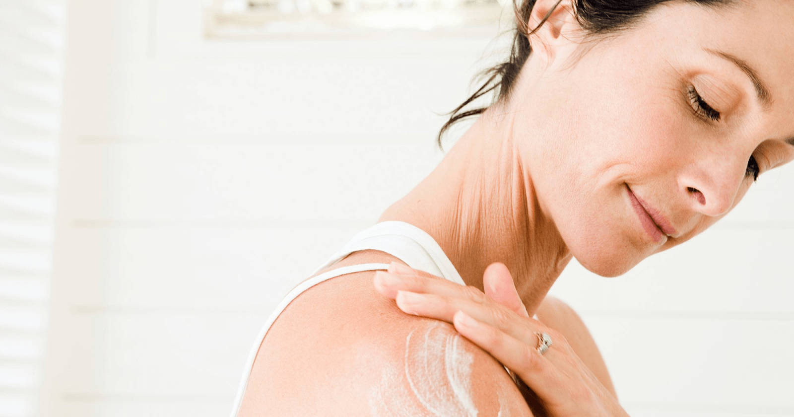 woman applying cream to her shoulder