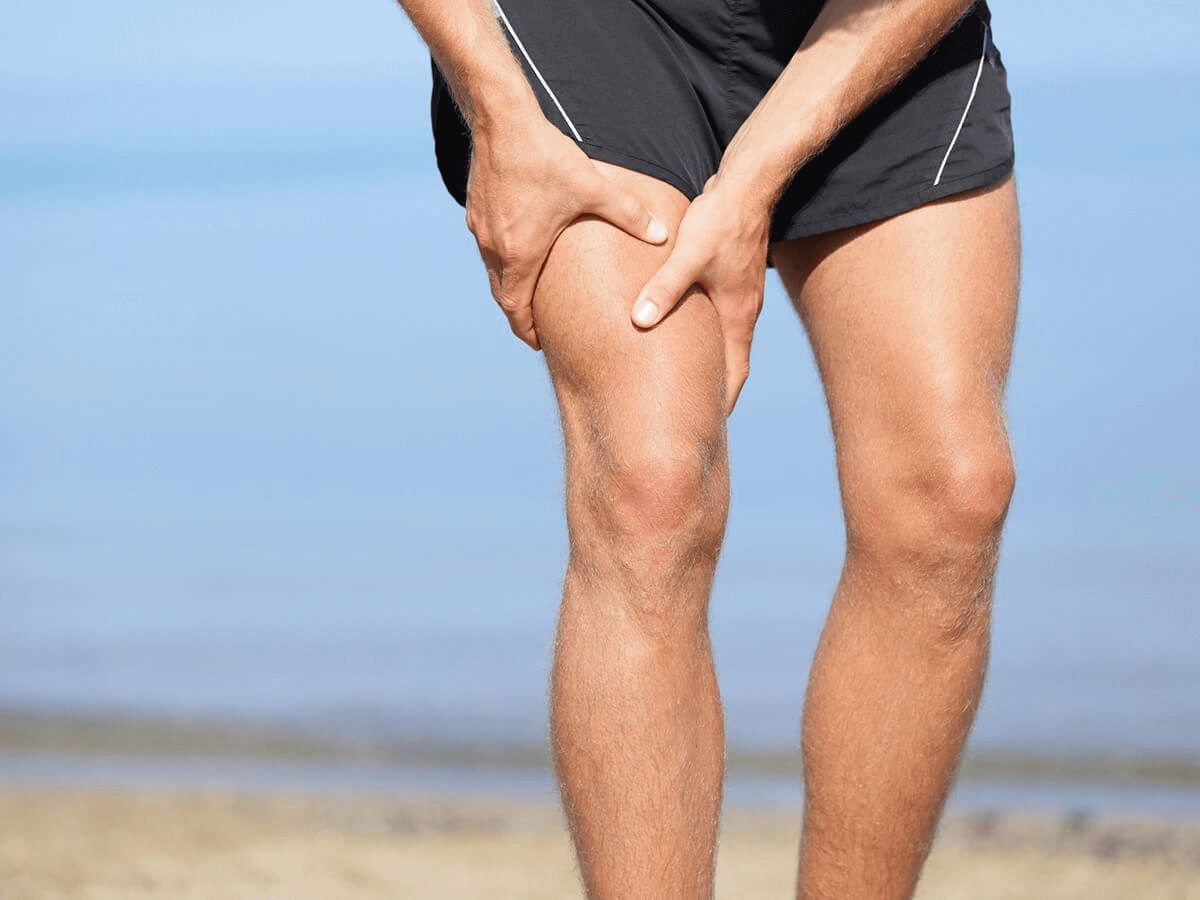 A man holding his right leg as if he has a sudden muscle cramp or pain.