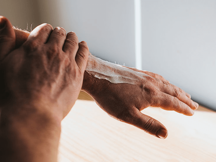 hands rubbing in cream on the back of their hand and forearm