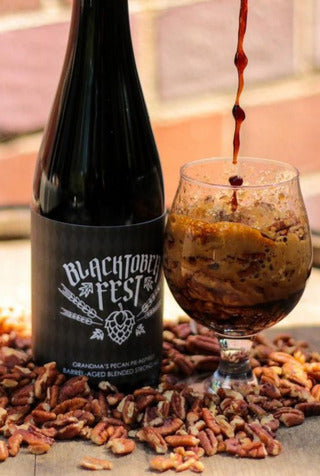 Bottle of Mike Jordan's Pecan Pie Ale surrounded by pecans while a glass beside it is filled