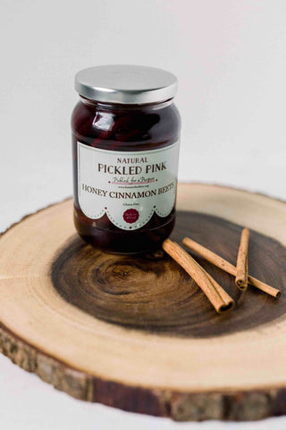 A jar of pickled beets by Pickled Pink Foods with cinnamon sticks on wood