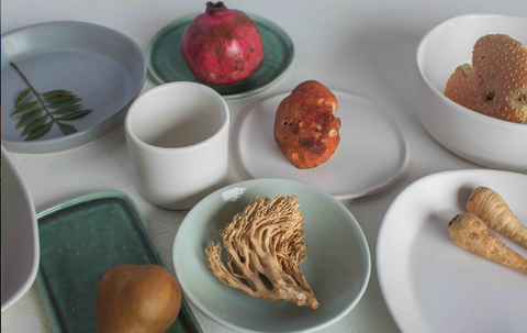 Haand ceramics with pomegranates and whole foods on a table