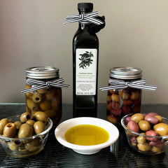 Table with Olinda Olives olive oil in bottle and in a bowl, and two different bowls of olives