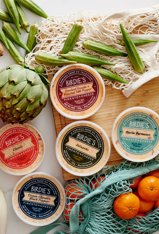 Birdie's Pimento cheese tubs surrounded by fresh fruit and veggies on a cutting board