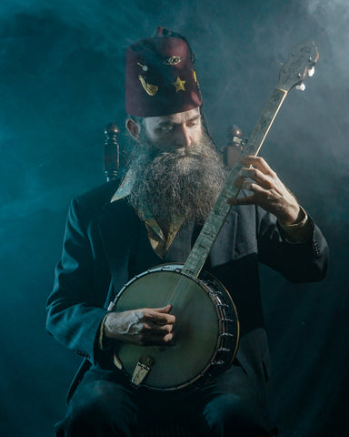 Aaron Jonah Lewis in fez playing banjo. 