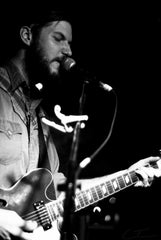 Chris Bathgate playing guitar on stage. 