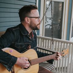 Kyle Rasche playing guitar on the porch. 