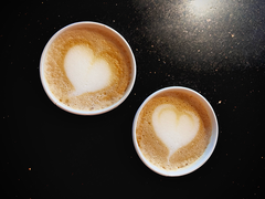 Two coffee cups with foam hearts.