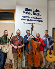 Round Creek String Band poses in front of a banner for Blue Lake Public Radio.