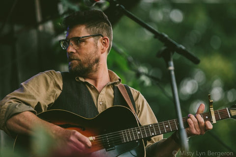 Rollie Tussing playing guitar outdoors. 