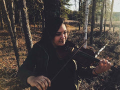 Ruby John playing fiddle in the woods.