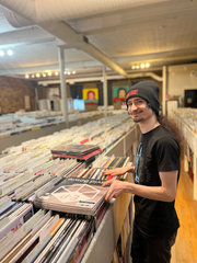 Vertigo staffer standing by record racks.