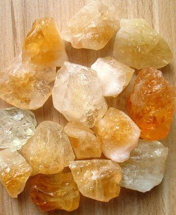pieces of raw citrine stones placed on a wooden surface top flat lay view