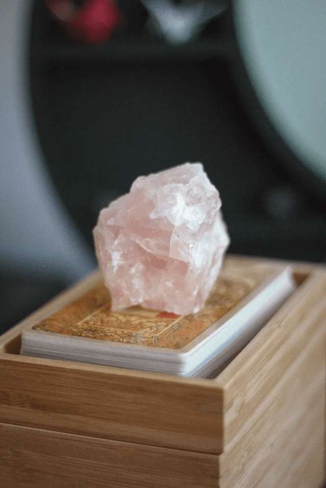 piece of pink crystal rock placed on a deck of tarot cards