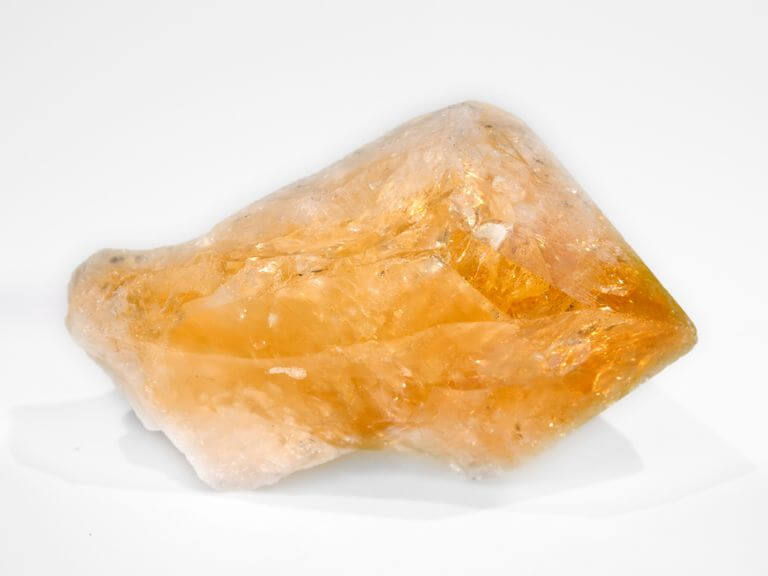 one piece of raw unpolished citrine white background close up view