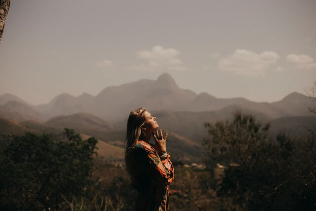 woman in red jacket standing near mountains