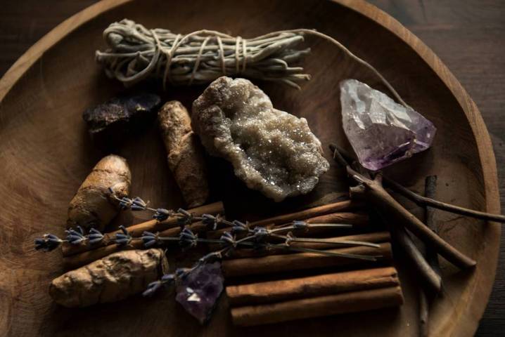 assorted arrangement of dried sticks herbs raw crystal rocks placed on a wooden plate