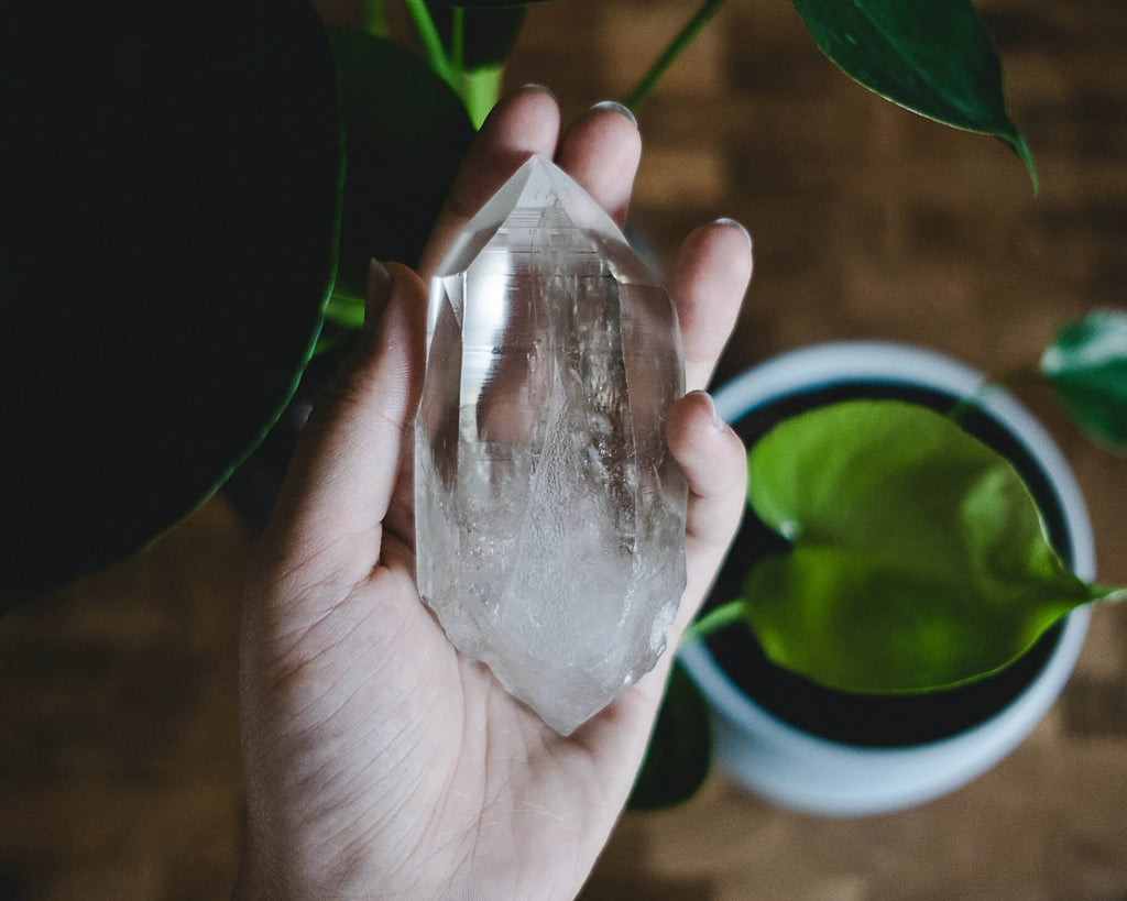 hand grasping a large piece of prism shaped clear crystal
