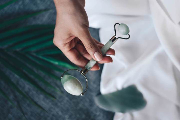 hand holding green jade roller and gua sha below top view