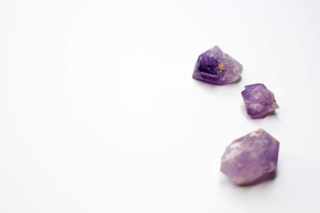 three tiny pieces of raw amethyst white background