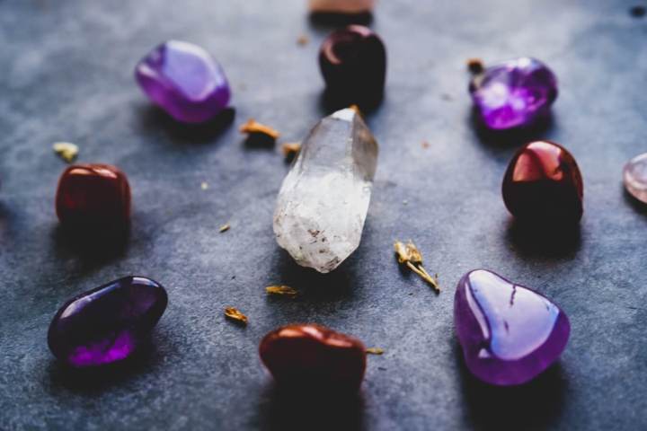 purple and red smooth stones arranged in a circle with a clear crystal in the center