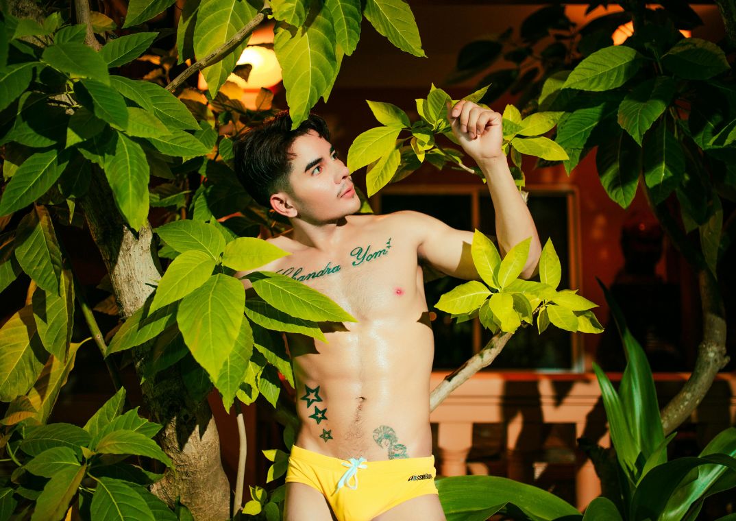 Man wearing yellow briefs amngst leaves