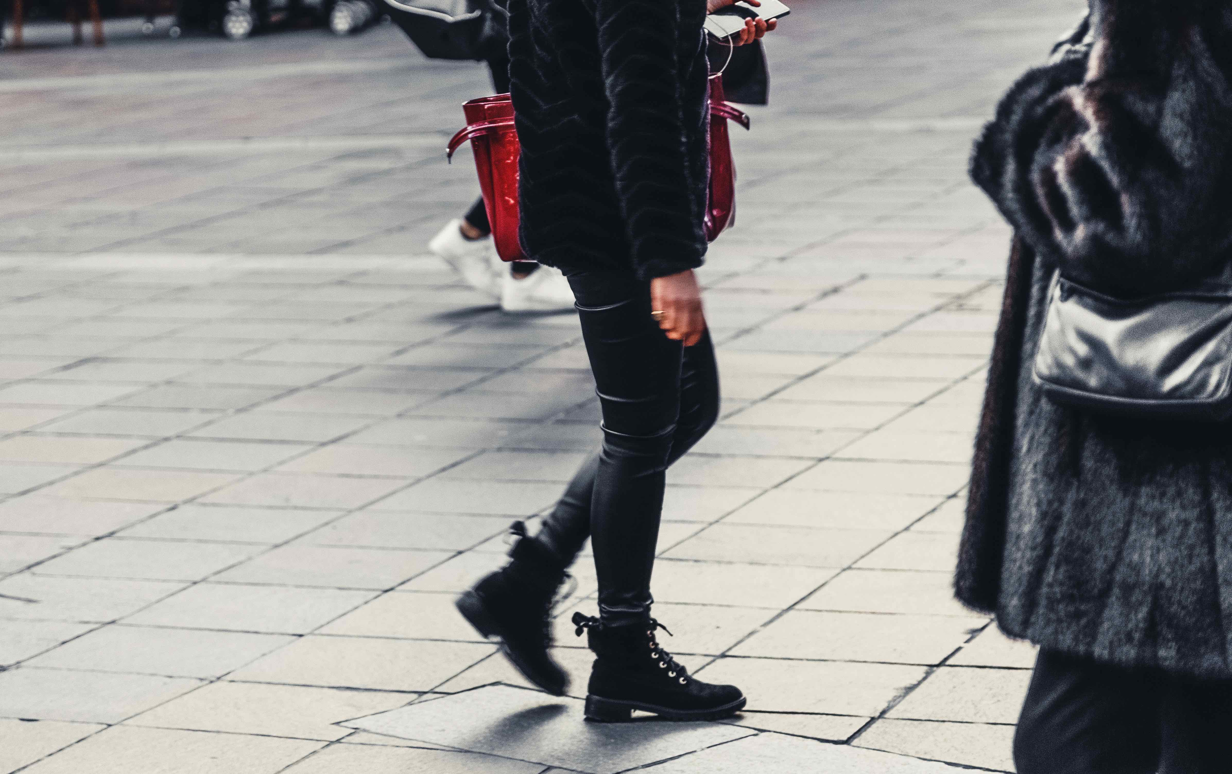 A woman in black boots walking on a street.