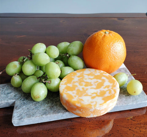 grapes, cheese, and a orange on a charcuterie board
