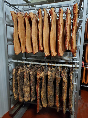 Original and pepper bacon slabs in the cooler after they have been smoked