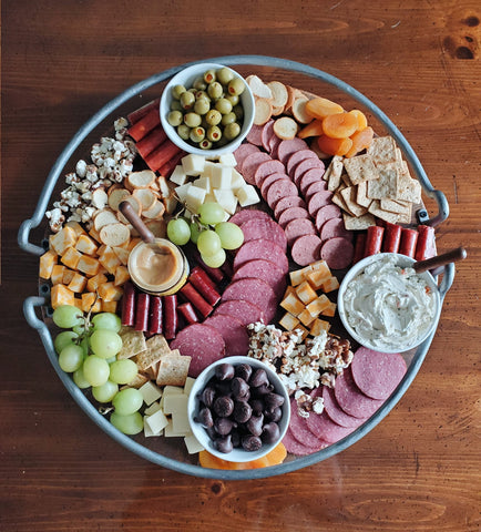 various fruits, crackers, meats, cheeses, olives, spreads, and wilbur buds on a charcuterie board