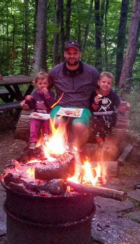 Branson with his kids in front of a fire pit in the woods