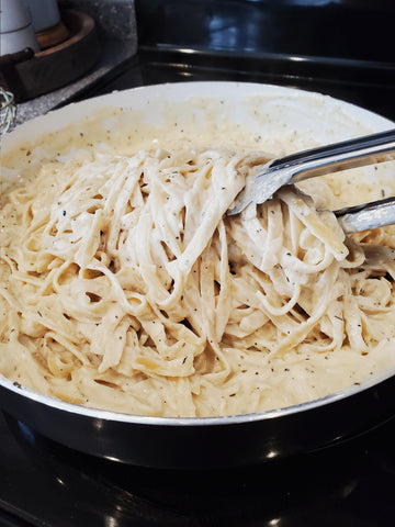 tossing the sauce with the fettuccine noodles