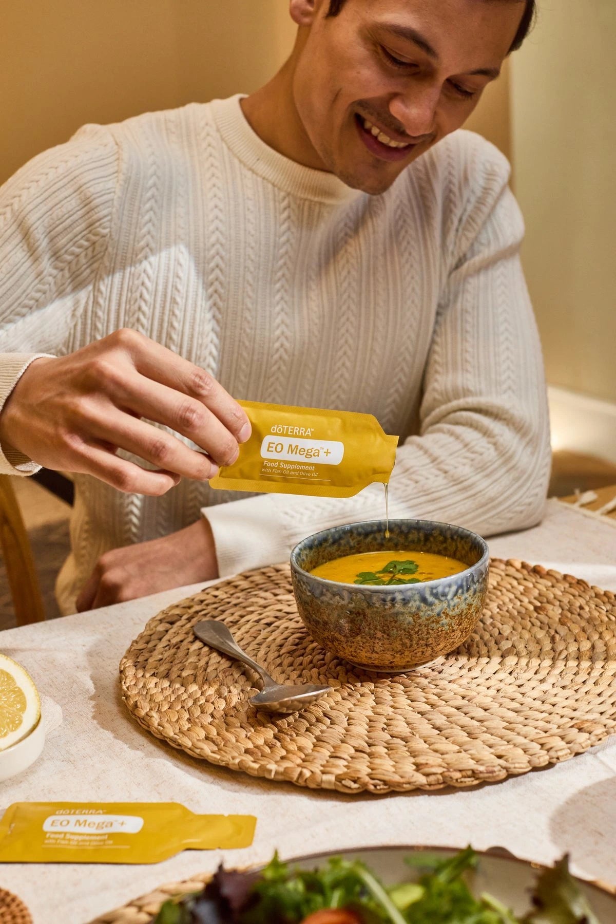 Homem a adicionar EO Mega+ da doTERRA à sopa para reforçar o bem-estar