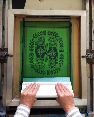 Karoline making a screen print of a decorative folk style pair of hands