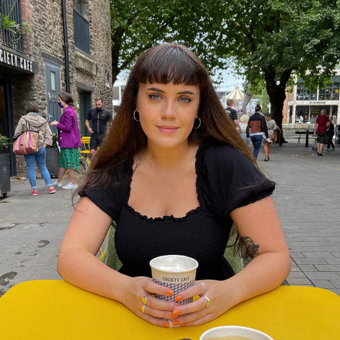 Eva sits outside a cafe enjoying a cup of coffee