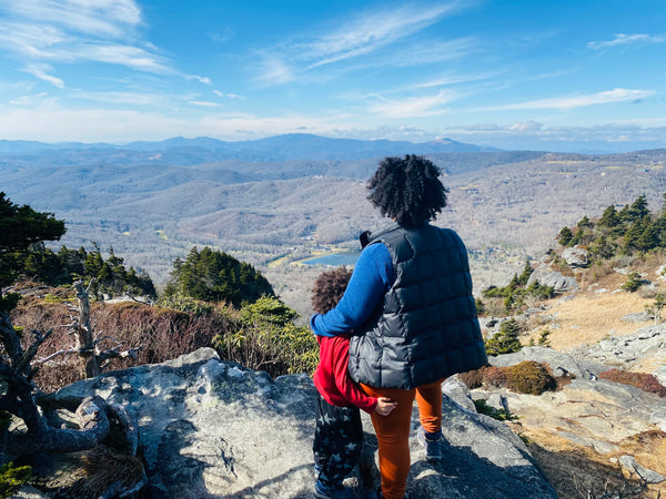 Mother and son hiking peer out over mountain