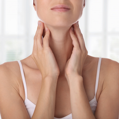 Woman holding neck where thyroid is