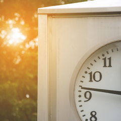 The left side of an outside clock with the sun shining in from behind it