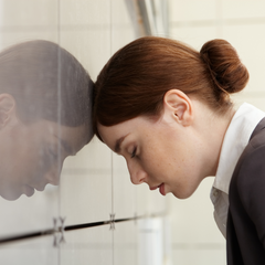 Fatigued woman leaning head against a wall