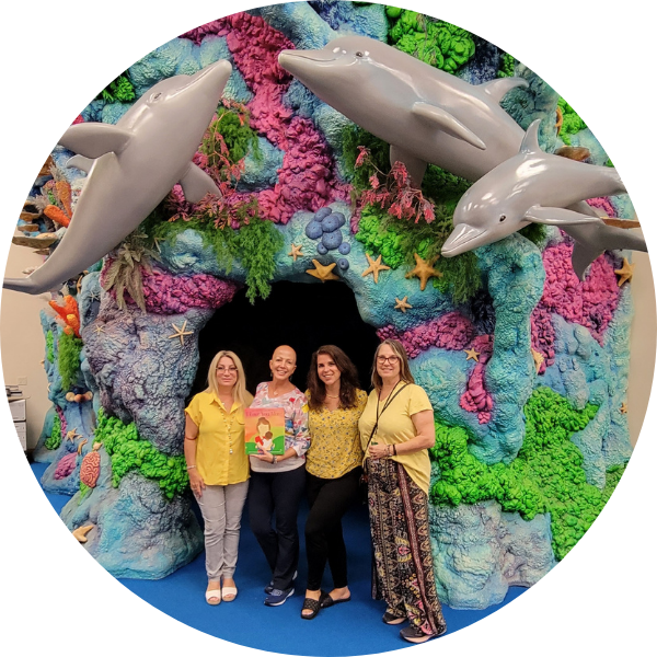 Laura Duksta smiles with three educators in front of a marine life installation at a school visit.