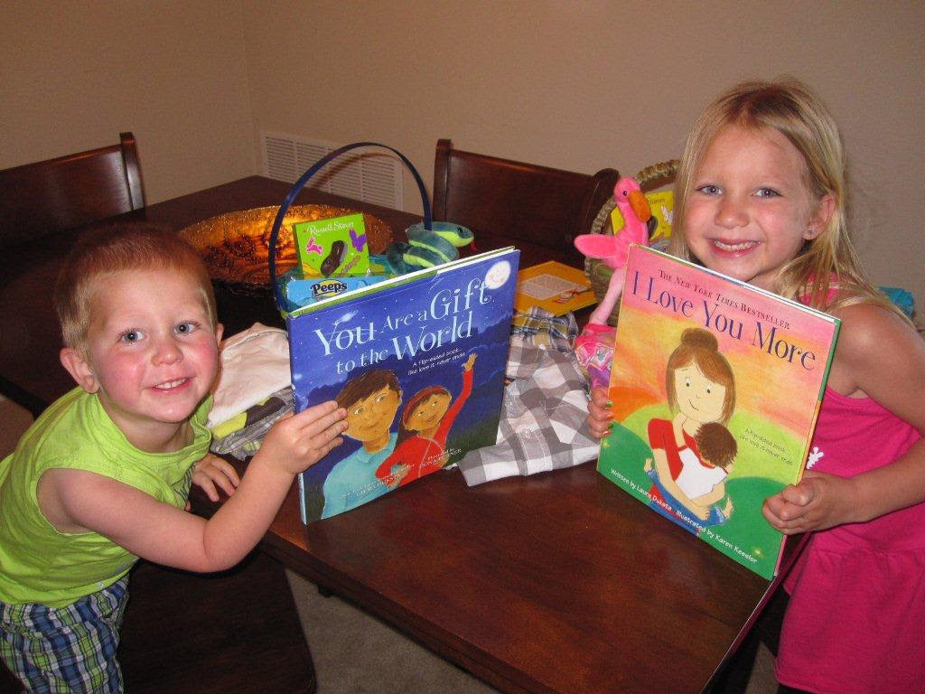 A boy holds a copy of Laura Duksta's "You Are a Gift to the World" and a girl hold a copy of "I Love You More".