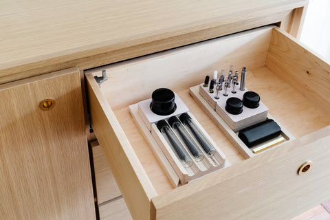 Lockable drawer in Forti Goods Eleanor cabinet is open to show Forti Goods organizational accessories in Petal pink linoleum over Baltic Birch wood finish, and miscellaneous CBD products.