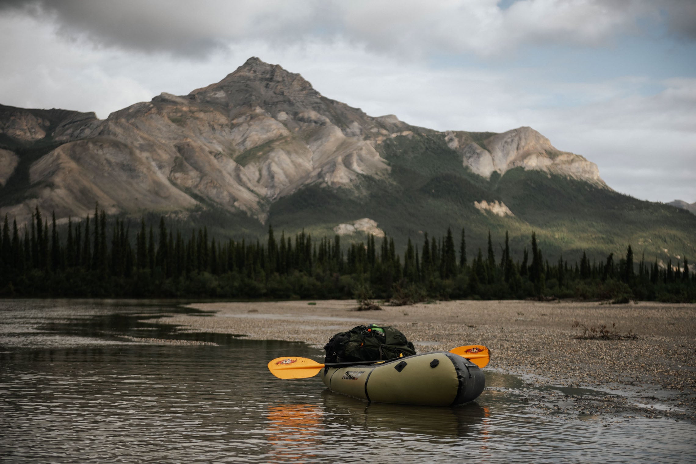 Packraft at the shore with arctic mountain in background