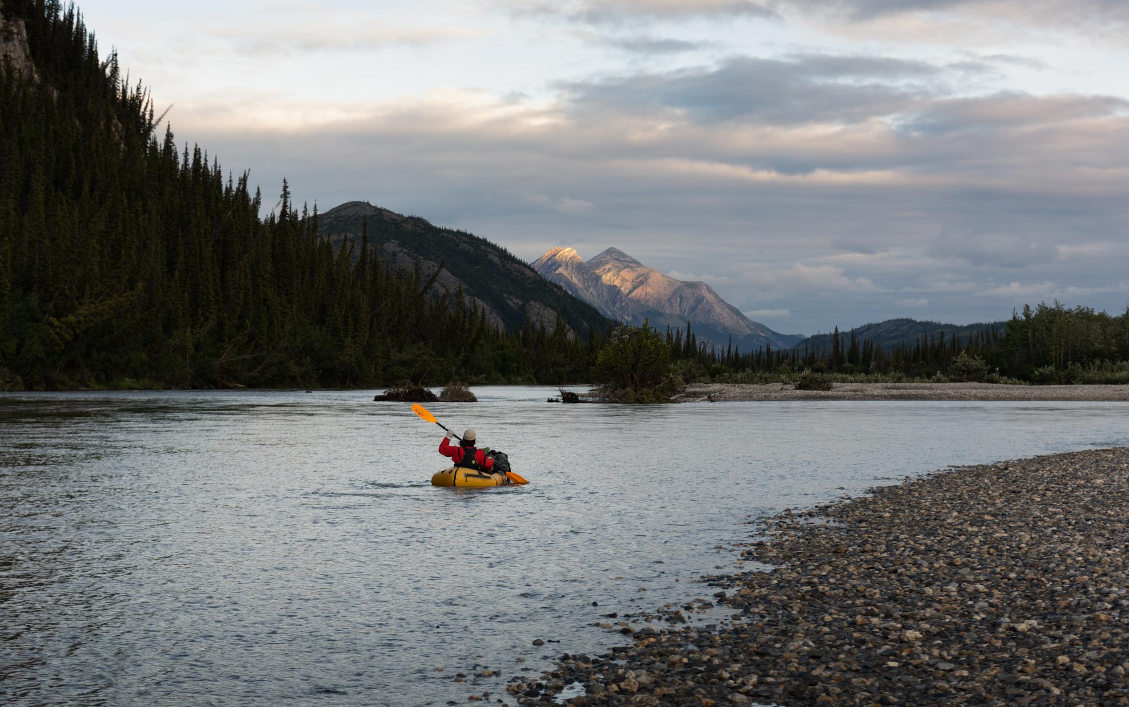 Packrafting in a lake at dawn with a snow capped mountain in the background