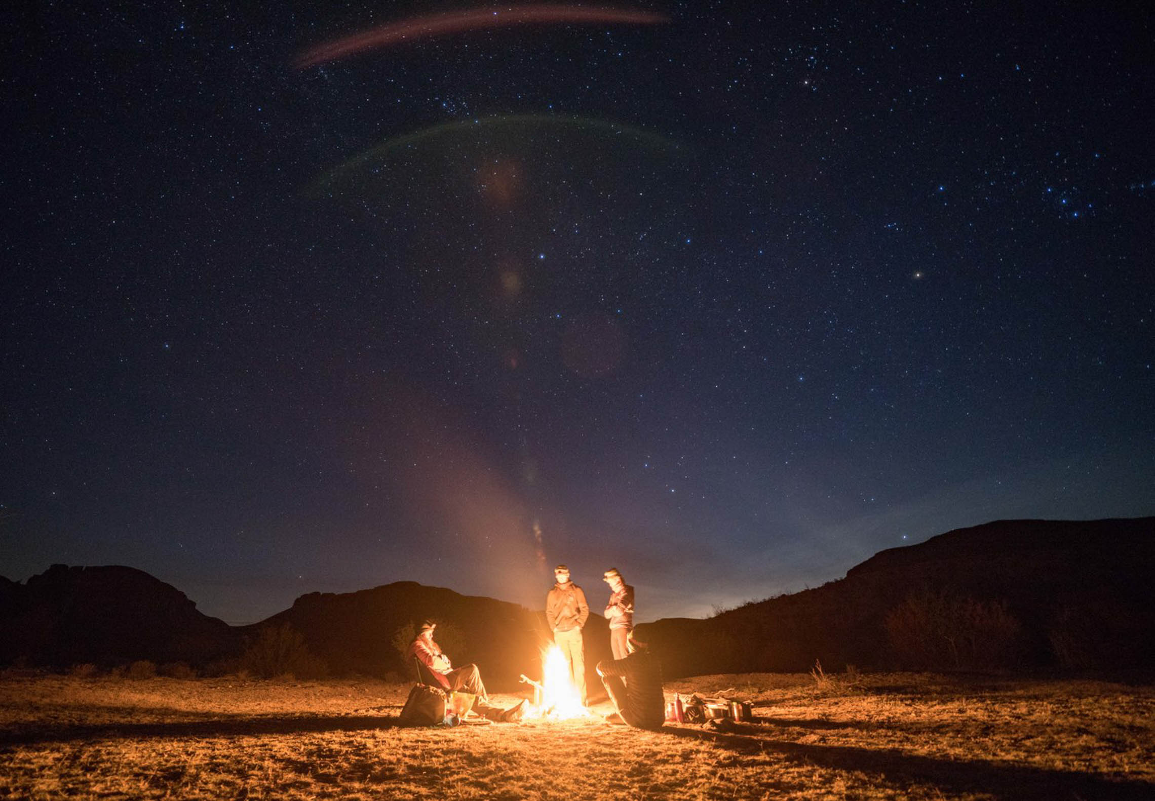 Sitting around campfire under a starry night sky. Rio Grande Packrafting Kokopelli