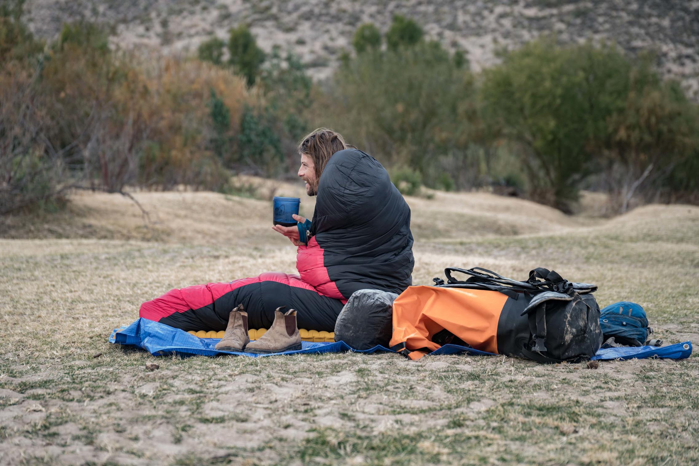 Man drinking coffee in the morning while camping. Rio Grande Packrafting Kokopelli